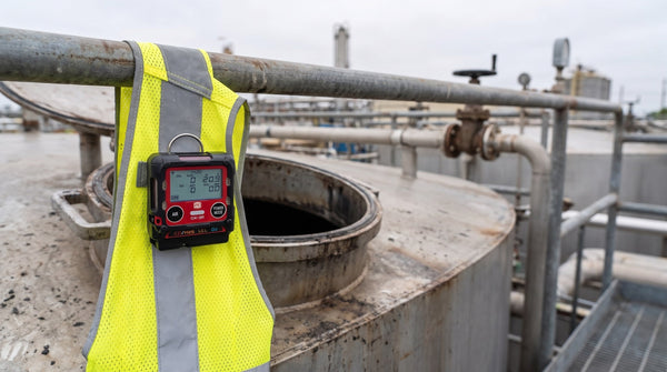 Moniteur RKI GX-3R fixé à une veste haute visibilité près d'un trou d'homme de réservoir industriel