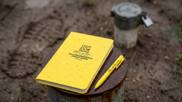 Yellow Rite in the Rain Environmental Field Book and clicker pen on a rusty well casing in the rain