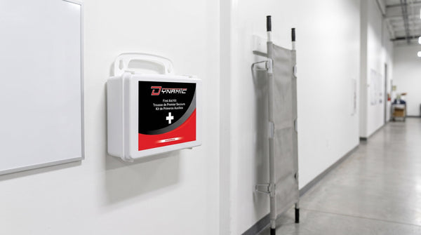 Dynamic first aid kit wall-mounted beside a stretcher in a workplace corridor