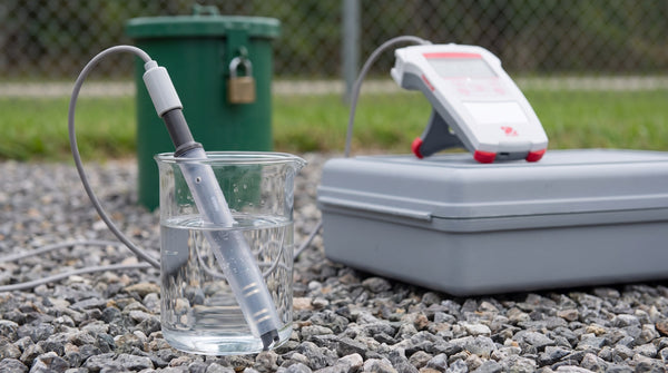 Portable conductivity meter and probe beside a groundwater monitoring well